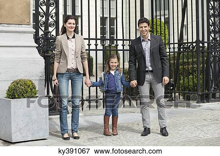 Stock Photo - Portrait of a girl standing with her parents. Fotosearch