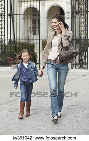 Stock Image - Portrait of a girl walking with her mother. Fotosearch
