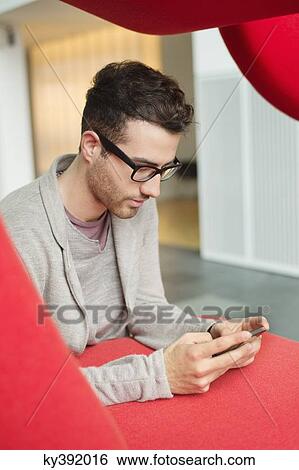 Stock Photograph - Businessman text messaging in an office. Fotosearch