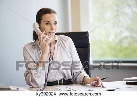 Businesswoman talking on a landline phone in an office View Large Photo Image Picture - Businesswoman talking on a landline phone in an office. Fotosearch