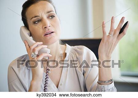 Businesswoman talking on a landline phone in an office View Large Photo Image Picture - Businesswoman talking on a landline phone in an office. Fotosearch
