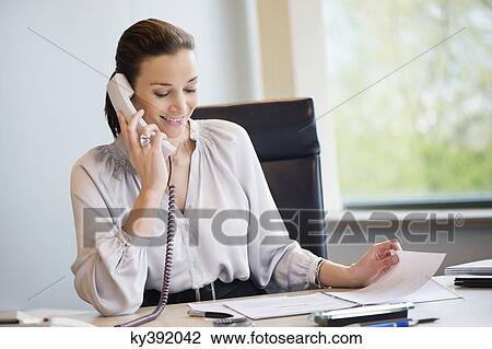 Businesswoman talking on a landline phone in an office View Large Photo Image Stock Image - Businesswoman talking on a landline phone in an office. Fotosearch