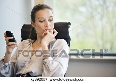 Businesswoman text messaging on a mobile phone in an office View Large Photo Image Stock Photo - Businesswoman text messaging on a mobile phone in an office. Fotosearch