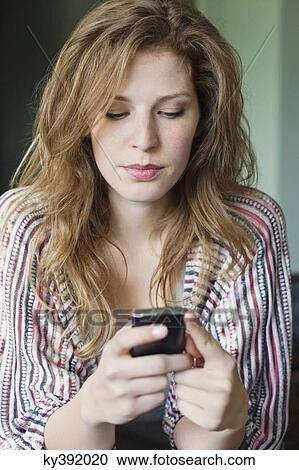 Stock Image - Close-up of a beautiful woman text messaging on a mobile phone. Fotosearch