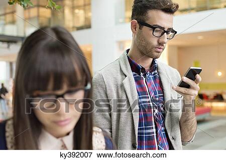 Fashion designer text messaging on a mobile phone in an office View Large Photo Image Stock Photo - Fashion designer text messaging on a mobile phone in an office. Fotosearch