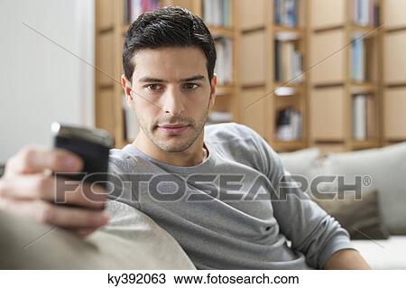 Man resting on a couch and using a mobile phone View Large Photo Image Stock Image - Man resting on a couch and using a mobile phone. Fotosearch