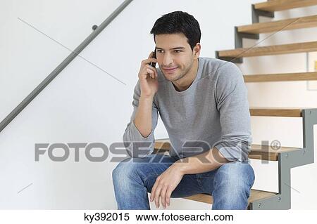 Stock Photography - Man sitting on stairs and talking on a mobile phone. Fotosearch