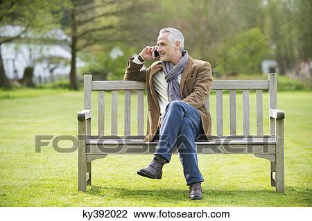 Stock Image - Man talking on a mobile phone in a park. Fotosearch
