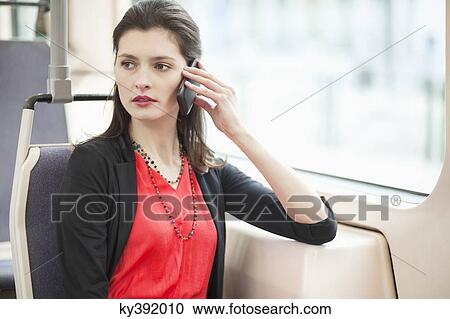 Woman traveling in a bus and talking on a mobile phone View Large Photo Image Stock Image - Woman traveling in a bus and talking on a mobile phone. Fotosearch