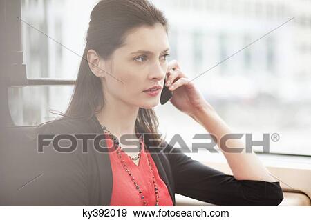 Woman traveling in a bus and talking on a mobile phone View Large Photo Image Stock Photo - Woman traveling in a bus and talking on a mobile phone. Fotosearch