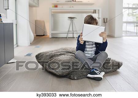 Boy hiding his face with a digital tablet View Large Photo Image Stock Image - Boy hiding his face with a digital tablet. Fotosearch