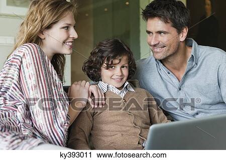 Boy using a laptop with his parents at home View Large Photo Image Stock Image - Boy using a laptop with his parents at home. Fotosearch