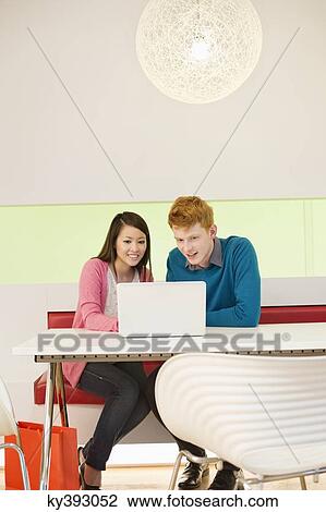 Business couple working on a laptop in an office View Large Photo Image Stock Image - Business couple working on a laptop in an office. Fotosearch