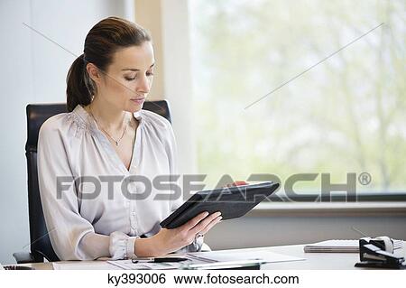 Stock Photograph - Businesswoman using a digital tablet in an office. Fotosearch