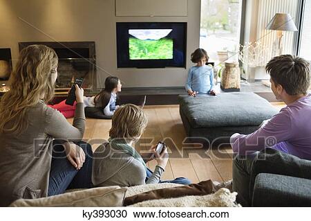 Family using electronic gadgets in a living room View Large Photo Image Stock Image - Family using electronic gadgets in a living room. Fotosearch