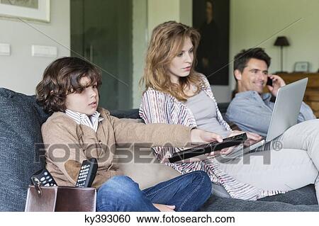 Family using electronic gadgets in a living room View Large Photo Image Stock Image - Family using electronic gadgets in a living room. Fotosearch