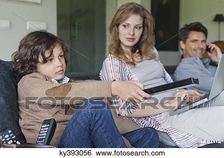 Stock Photograph - Family using electronic gadgets in a living room. Fotosearch
