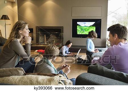 Family using electronic gadgets in a living room View Large Photo Image Stock Photograph - Family using electronic gadgets in a living room. Fotosearch