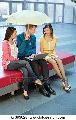Male business executive using a laptop with his female colleagues and holding an umbrella View Large Photo Image Stock Photo - Male business executive using a laptop with his female colleagues and holding an umbrella. Fotosearch