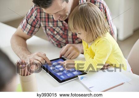 Stock Photography - Man teaching digital tablet to his daughter. Fotosearch