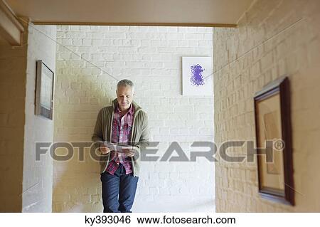 Man using a digital tablet in a corridor View Large Photo Image Stock Photograph - Man using a digital tablet in a corridor. Fotosearch