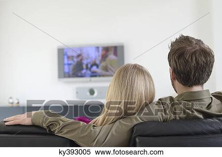 Rear view of a couple watching television View Large Photo Image Stock Photography - Rear view of a couple watching television. Fotosearch