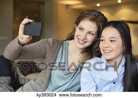 Picture - Woman and her daughter taking a picture of themselves with a camera phone. Fotosearch