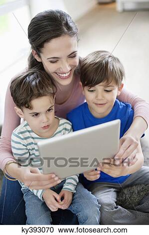 Woman showing a digital tablet to their children View Large Photo Image Stock Image - Woman showing a digital tablet to their children. Fotosearch