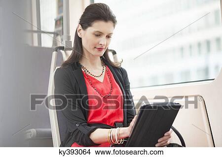Woman traveling in a bus using a digital tablet View Large Photo Image Picture - Woman traveling in a bus using a digital tablet. Fotosearch