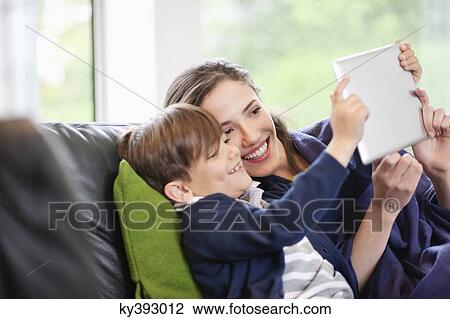 Woman with her son looking at a digital tablet and smiling View Large Photo Image Stock Image - Woman with her son looking at a digital tablet and smiling. Fotosearch