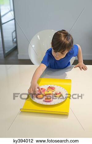 Boy picking a cup cake from plate View Large Photo Image Stock Image - Boy picking a cup cake from plate. Fotosearch
