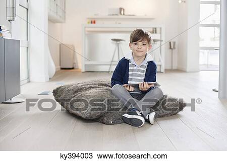 Stock Image - Portrait of a boy holding a digital tablet. Fotosearch
