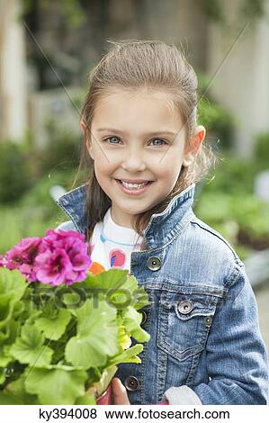 Stock Photo - Portrait of a girl holding a potted plant. Fotosearch