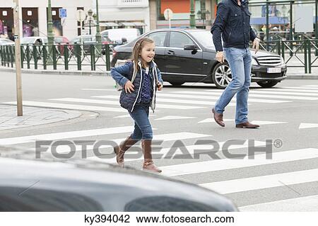 Stock Image - Schoolgirl crossing a road. Fotosearch