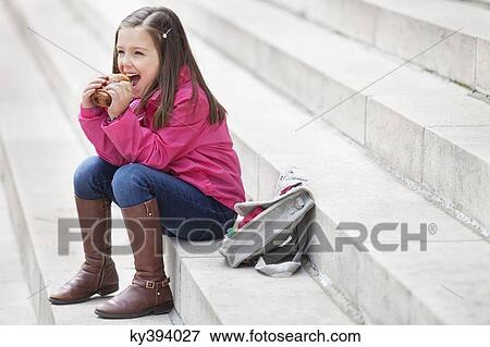 Schoolgirl sitting on the steps and eating pain au chocolat View Large Photo Image Stock Photo - Schoolgirl sitting on the steps and eating pain au chocolat. Fotosearch