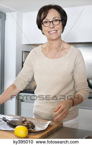 Elderly woman preparing seafood in a kitchen View Large Photo Image Stock Image - Elderly woman preparing seafood in a kitchen. Fotosearch
