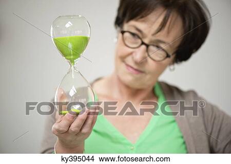Woman looking at an hourglass View Large Photo Image Picture - Woman looking at an hourglass. Fotosearch