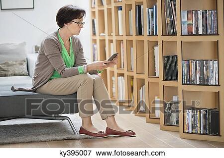 Woman sitting on a couch and reading a book View Large Photo Image Stock Photo - Woman sitting on a couch and reading a book. Fotosearch