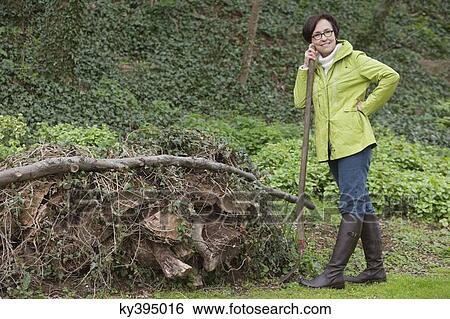 Woman standing with a shovel near a heap of rubbish View Large Photo Image Stock Photograph - Woman standing with a shovel near a heap of rubbish. Fotosearch