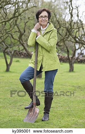 Woman standing with a shovel View Large Photo Image Stock Image - Woman standing with a shovel. Fotosearch