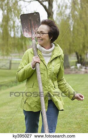 Woman walking with a spade in a park View Large Photo Image Stock Photo - Woman walking with a spade in a park. Fotosearch