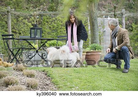 Couple playing with their pets in a garden View Large Photo Image Stock Image - Couple playing with their pets in a garden. Fotosearch