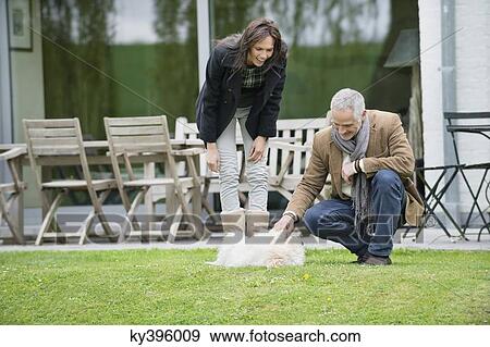 Couple playing with their pets in a garden View Large Photo Image Stock Photo - Couple playing with their pets in a garden. Fotosearch