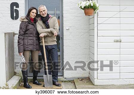 Couple standing at the doorway with a shovel View Large Photo Image Stock Photo - Couple standing at the doorway with a shovel. Fotosearch