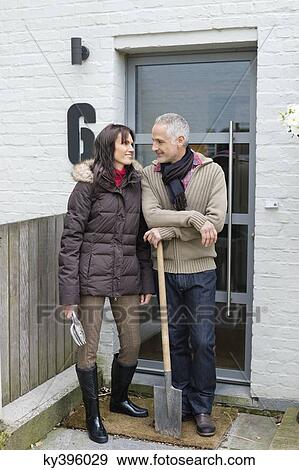 Couple standing at the doorway with a shovel View Large Photo Image Stock Photo - Couple standing at the doorway with a shovel. Fotosearch