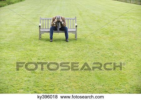 Depressed man sitting on a bench in a park View Large Photo Image Stock Photo - Depressed man sitting on a bench in a park. Fotosearch
