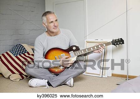 Stock Photography - Man playing a guitar at home. Fotosearch