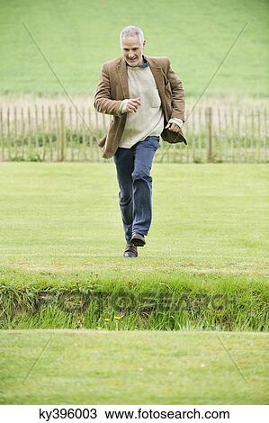 Man running in a field View Large Photo Image Stock Image - Man running in a field. Fotosearch