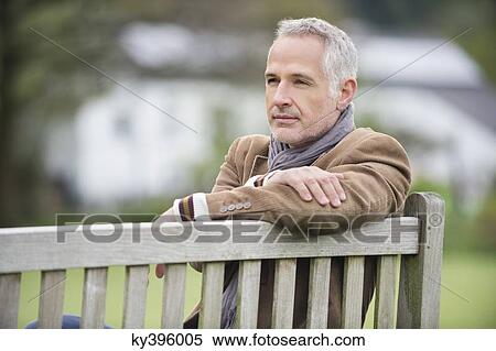 Stock Photography - Man sitting on a bench and thinking in a park. Fotosearch