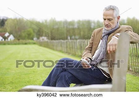Man text messaging on a mobile phone in a field View Large Photo Image Stock Image - Man text messaging on a mobile phone in a field. Fotosearch